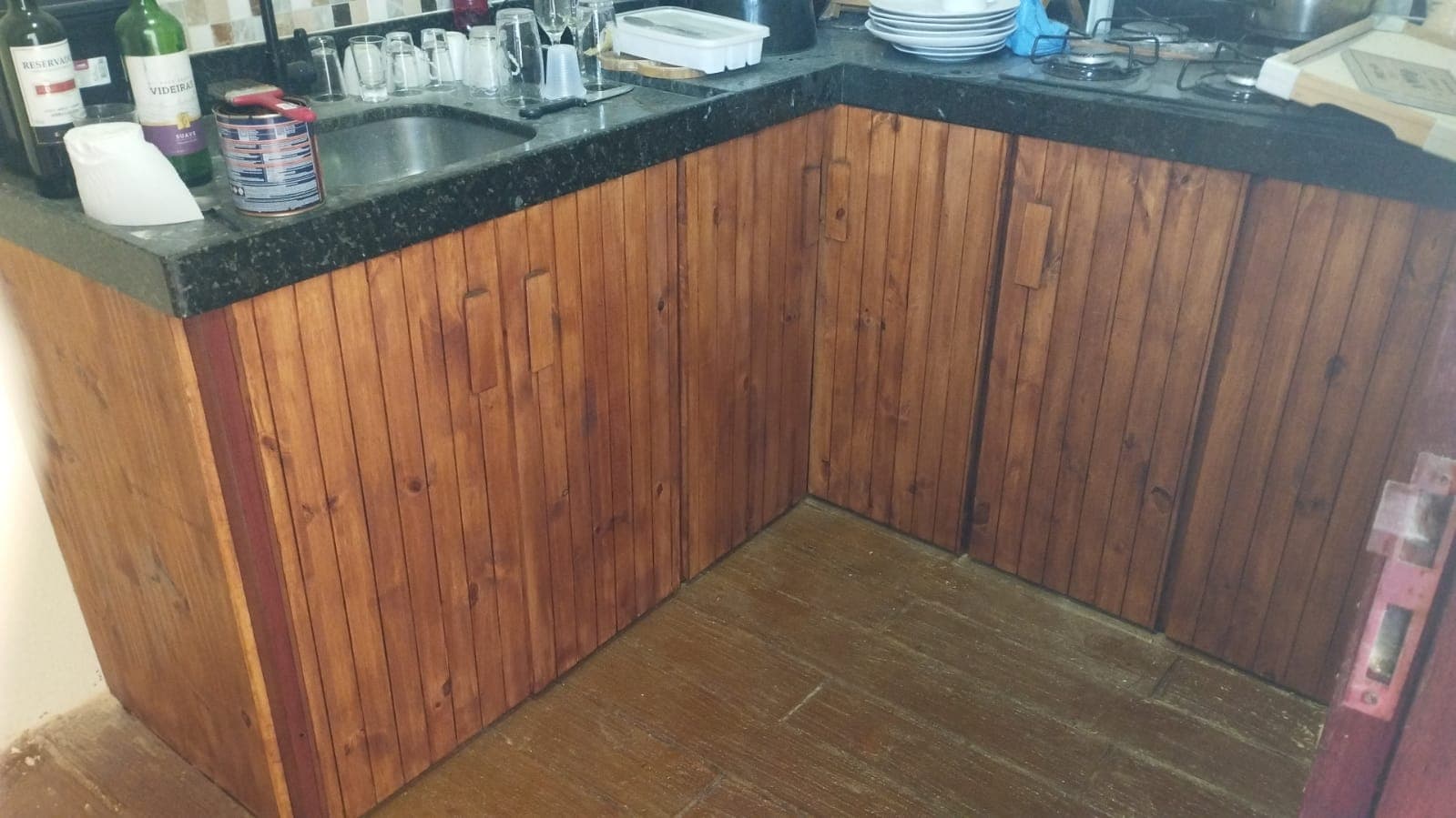 Armário de cozinha. Portas ripadas em madeira maciça sob bancada de granito.