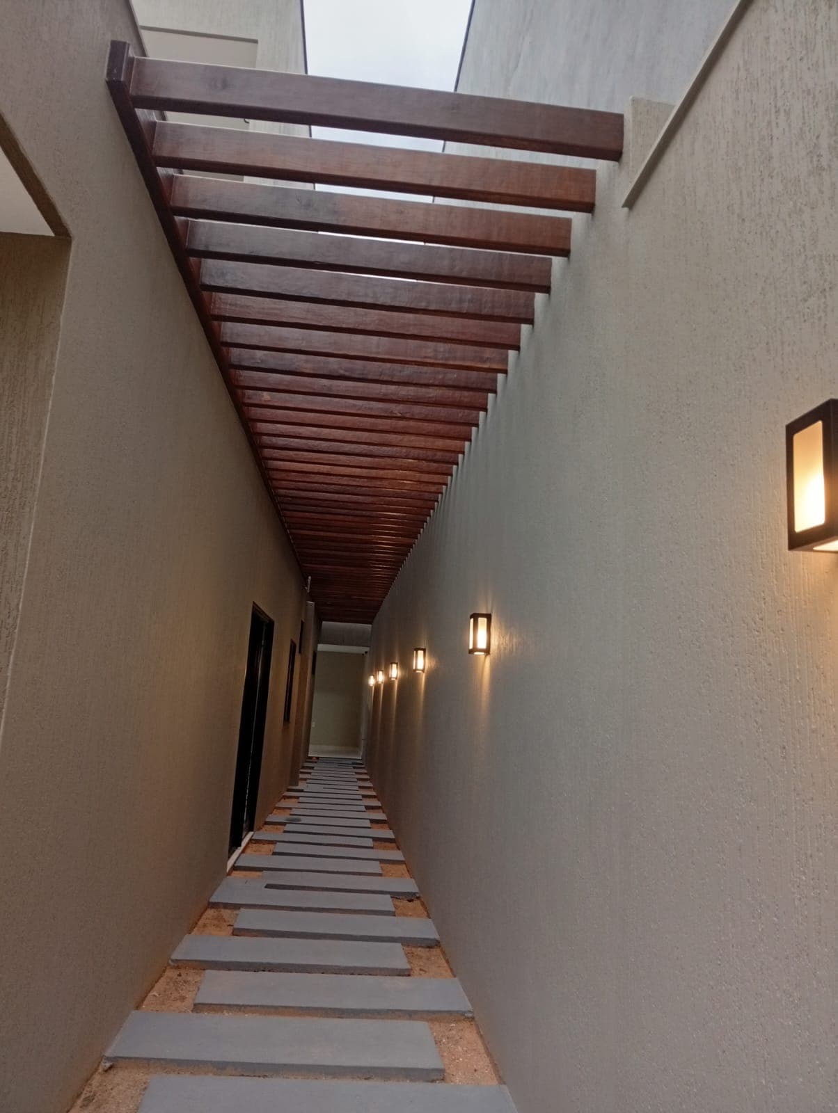 Pergolado de corredor. Ripado de madeira cobrindo o corredor lateral da casa.
